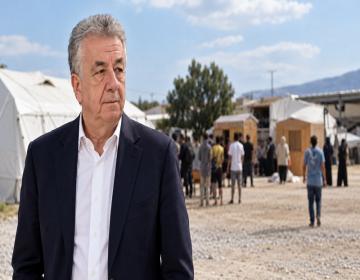 Ο περιφερειάρχης Κρήτης Σταύρος Αρναουτάκης με φόντο προσωρινή δομή φιλοξενίας μεταναστών.